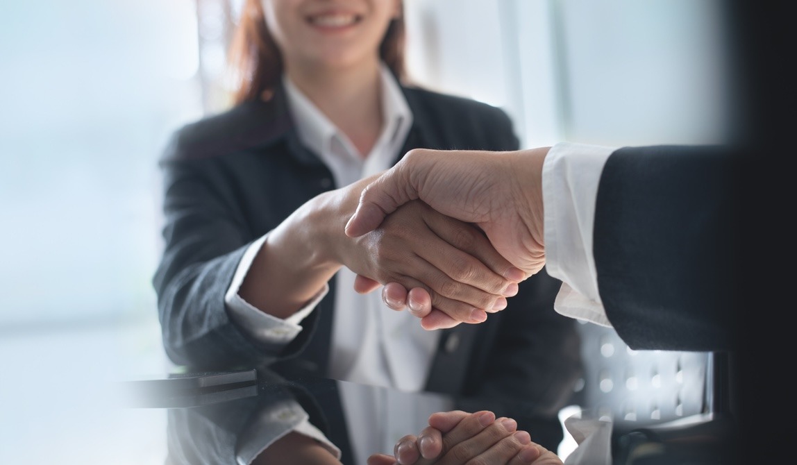 woman shaking hands with a man in a corporate setting