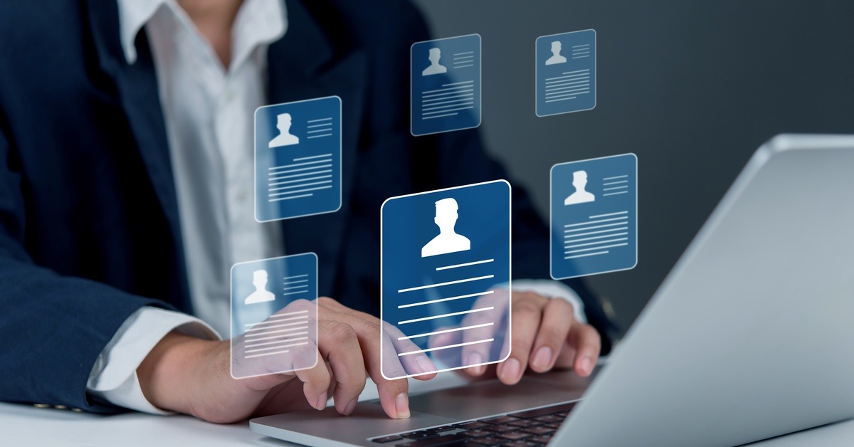 A person wearing business attire types on a laptop. Above the laptop is a graphic of different professional resumes.