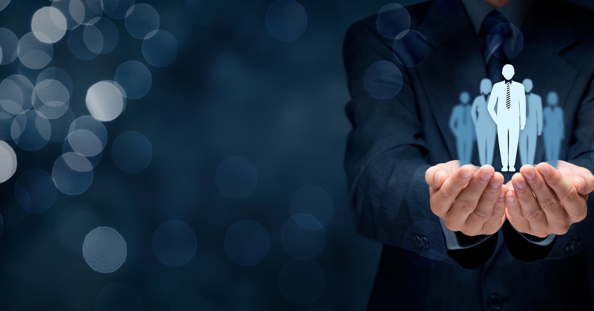 A business man holding out his hands and cupping a graphic of five business professionals standing together.